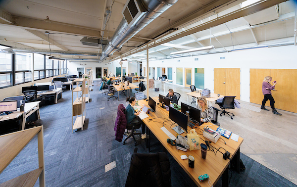 Flex desk seating by the windows at Platform Coworking